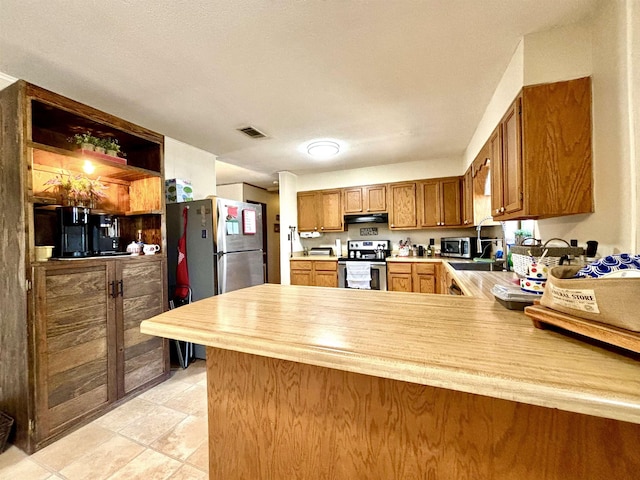 kitchen featuring light tile patterned flooring, appliances with stainless steel finishes, sink, and kitchen peninsula