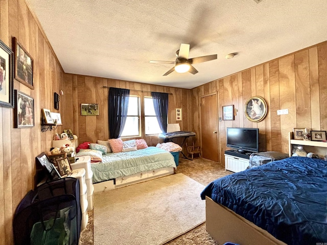 carpeted bedroom with ceiling fan, wooden walls, and a textured ceiling