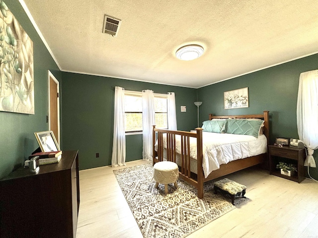 bedroom with ornamental molding, a textured ceiling, and light wood-type flooring