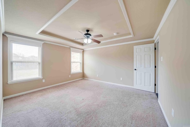 carpeted empty room with crown molding, ceiling fan, and a raised ceiling