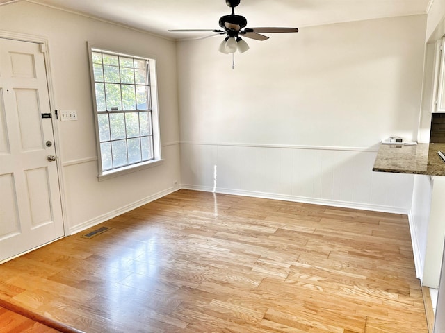 unfurnished dining area with ceiling fan and light wood-type flooring