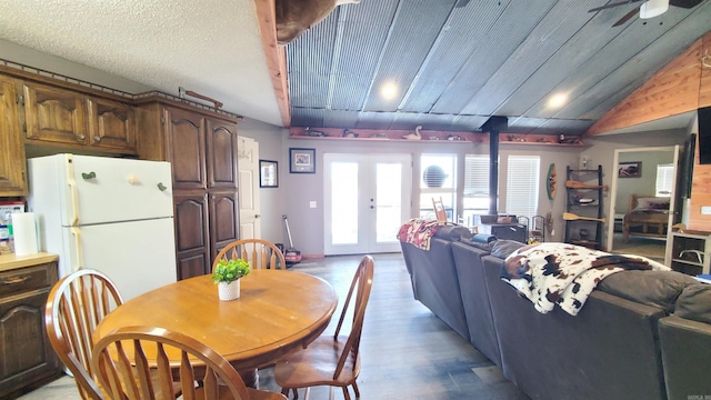 dining area with vaulted ceiling, a wood stove, ceiling fan, light hardwood / wood-style floors, and french doors