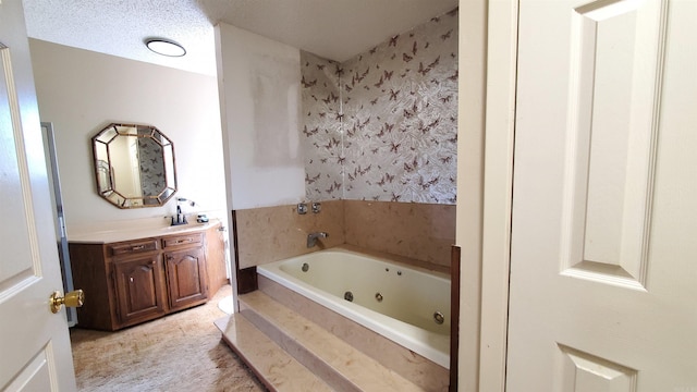 bathroom featuring vanity, a textured ceiling, and tiled tub