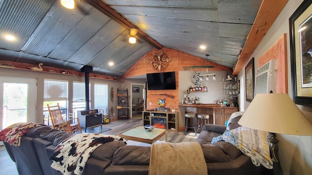 living room featuring hardwood / wood-style flooring, bar, lofted ceiling with beams, and a wood stove