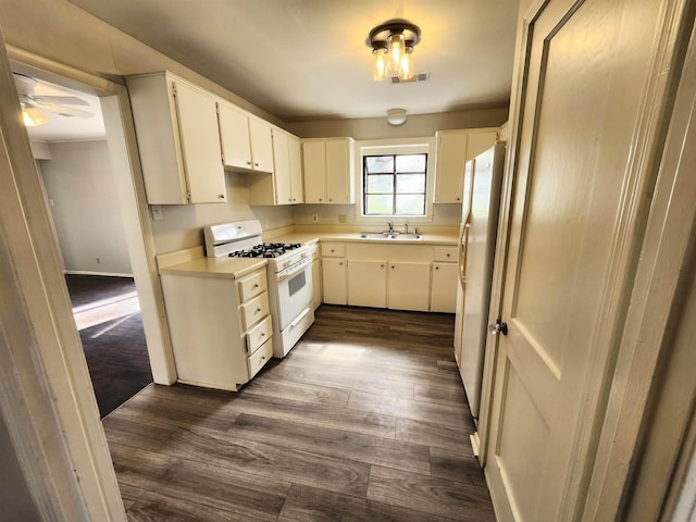 kitchen with sink, dark hardwood / wood-style floors, white range with gas stovetop, and white cabinets