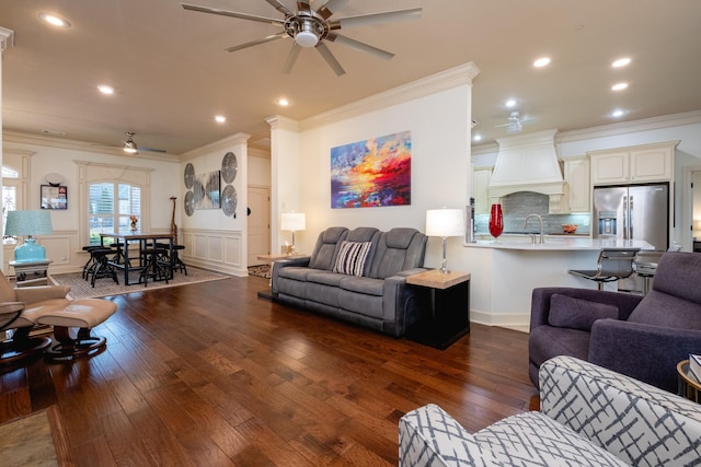 living room featuring dark hardwood / wood-style floors, ceiling fan, ornamental molding, and sink