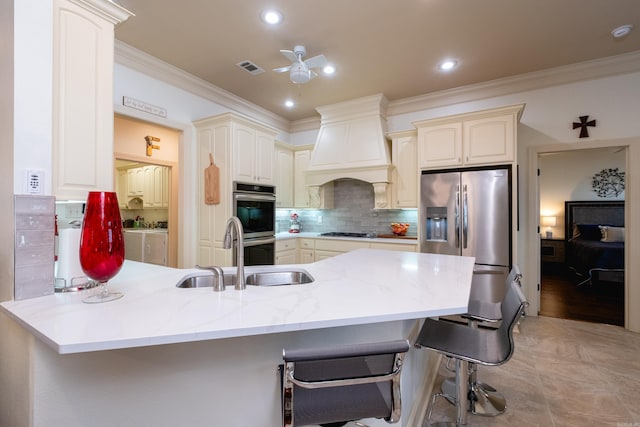 kitchen featuring kitchen peninsula, stainless steel appliances, sink, custom range hood, and a kitchen bar