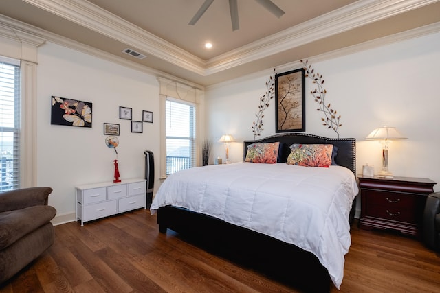 bedroom with a raised ceiling, dark wood-type flooring, crown molding, and multiple windows