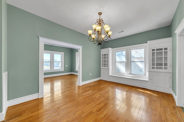 unfurnished dining area featuring light wood-type flooring and an inviting chandelier