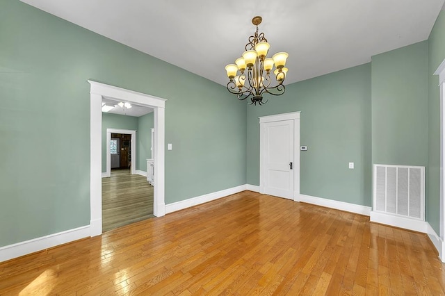 spare room featuring hardwood / wood-style flooring and a notable chandelier