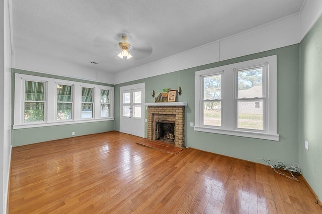 unfurnished living room with light hardwood / wood-style floors, ceiling fan, a textured ceiling, and a fireplace