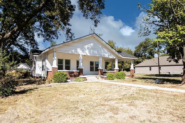 bungalow-style home featuring covered porch and a front lawn