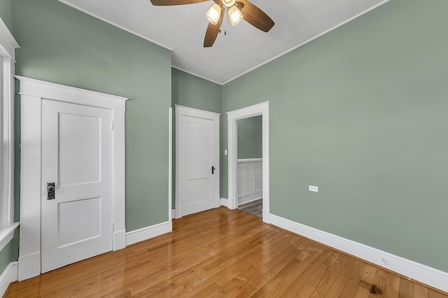 unfurnished bedroom featuring hardwood / wood-style floors, crown molding, and ceiling fan