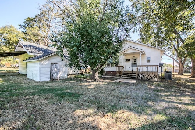 rear view of property with central air condition unit, a lawn, a wooden deck, and a storage shed