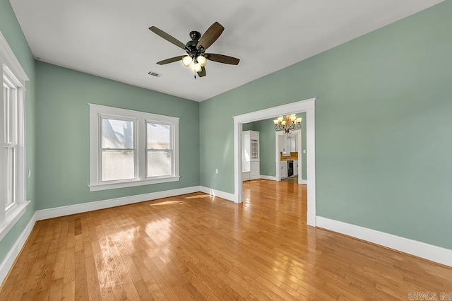 empty room with light wood-type flooring and ceiling fan with notable chandelier