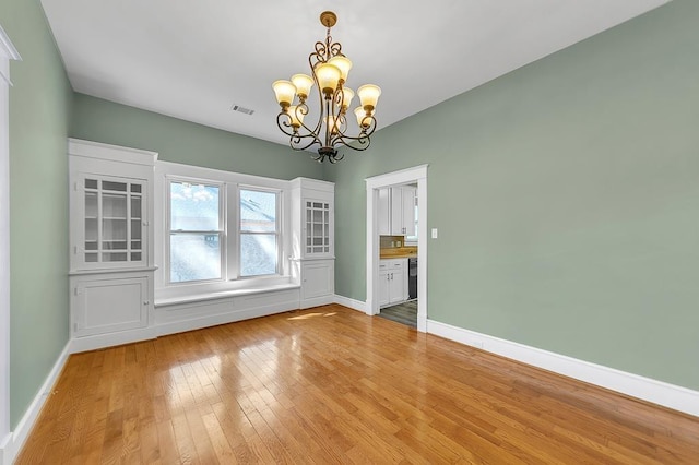 unfurnished dining area with a notable chandelier and wood-type flooring