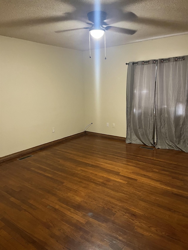 unfurnished room featuring ceiling fan, dark hardwood / wood-style flooring, and a textured ceiling