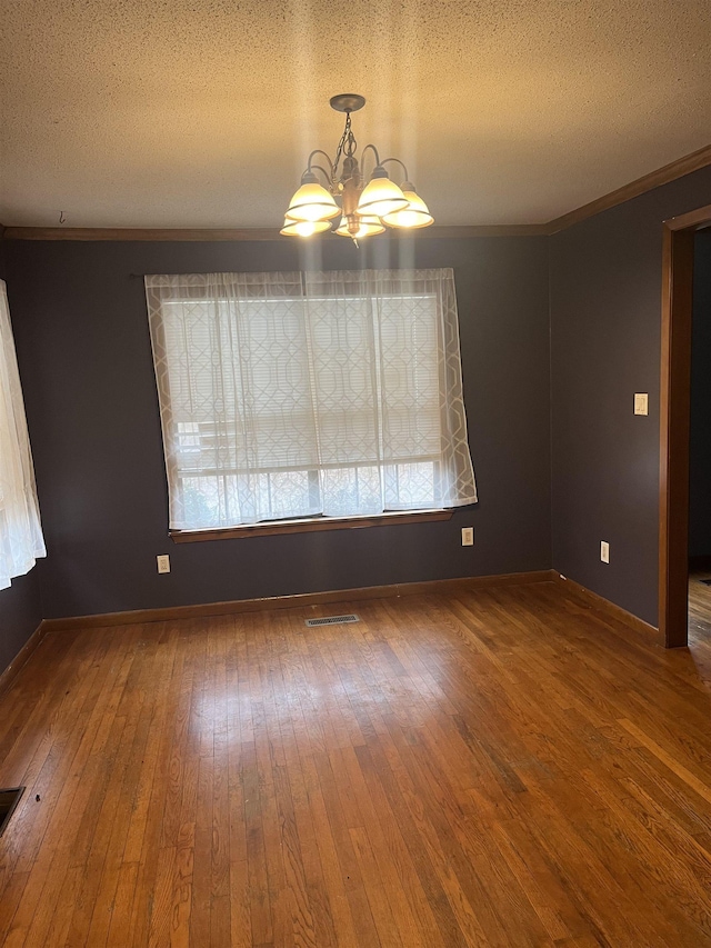 unfurnished room featuring a notable chandelier, crown molding, wood-type flooring, and a textured ceiling