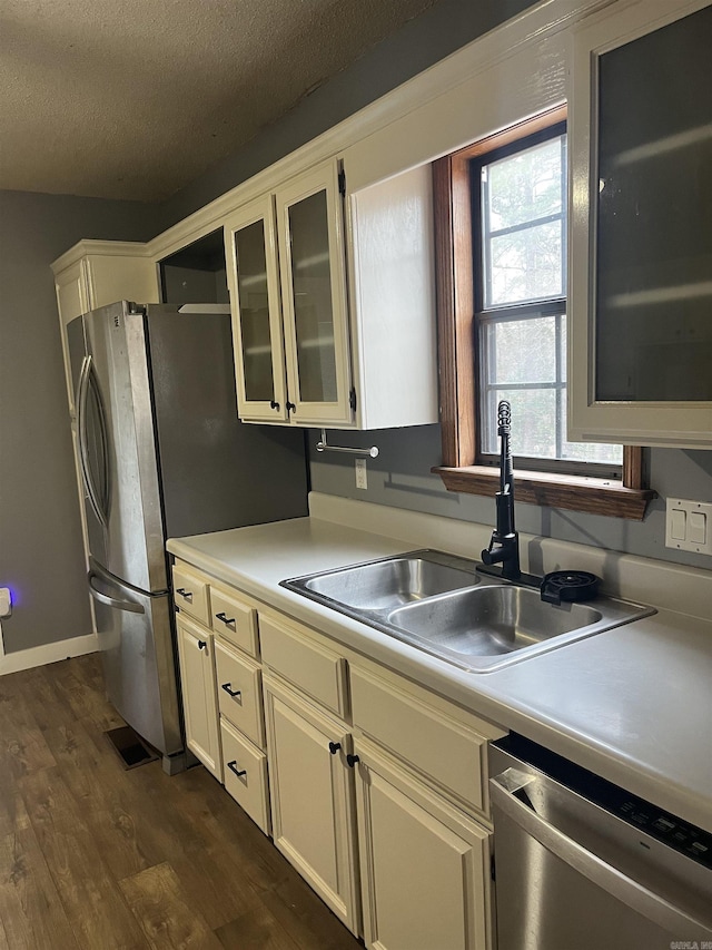 kitchen with appliances with stainless steel finishes, sink, dark wood-type flooring, and a textured ceiling