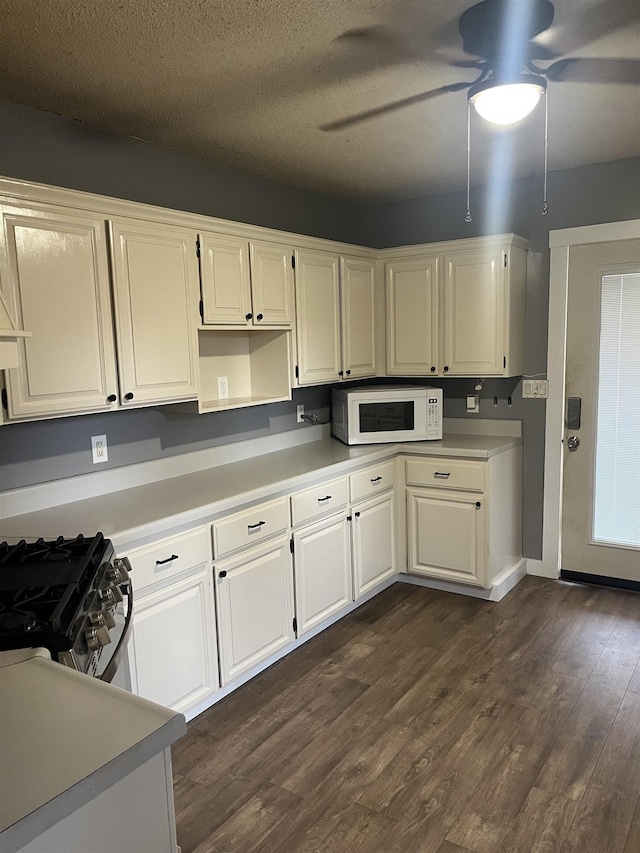 kitchen featuring a textured ceiling, ceiling fan, dark hardwood / wood-style flooring, stainless steel gas stove, and white cabinets