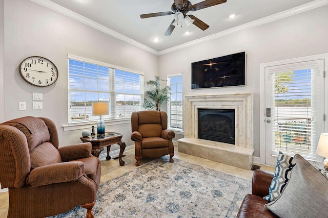 living room with a high end fireplace, a healthy amount of sunlight, crown molding, and ceiling fan