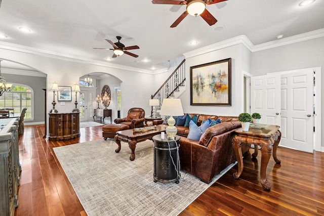 living room featuring dark hardwood / wood-style flooring, ornamental molding, and ceiling fan with notable chandelier