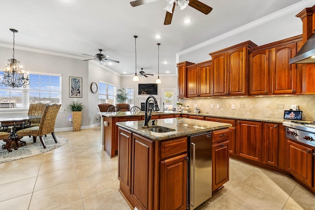 kitchen with an island with sink, sink, stone counters, and decorative light fixtures