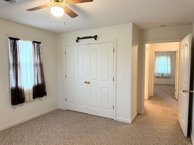 unfurnished bedroom with a textured ceiling, light carpet, ceiling fan, and a closet