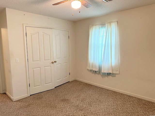 unfurnished bedroom with light carpet, a closet, ceiling fan, and a textured ceiling