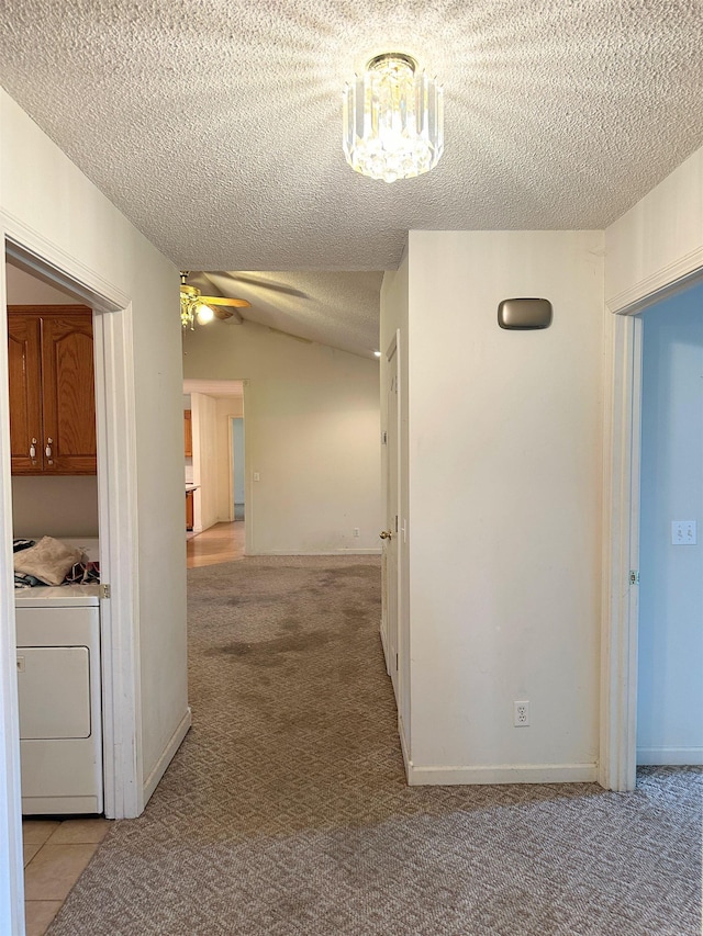 hall featuring washer / clothes dryer, light carpet, a textured ceiling, and lofted ceiling