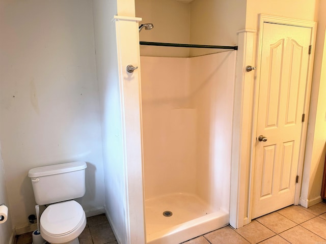 bathroom with a shower, tile patterned flooring, and toilet