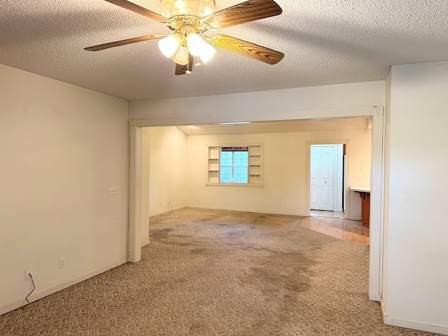 empty room with ceiling fan, carpet floors, and a textured ceiling