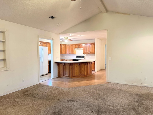 kitchen with kitchen peninsula, white fridge with ice dispenser, vaulted ceiling with beams, ceiling fan, and light carpet