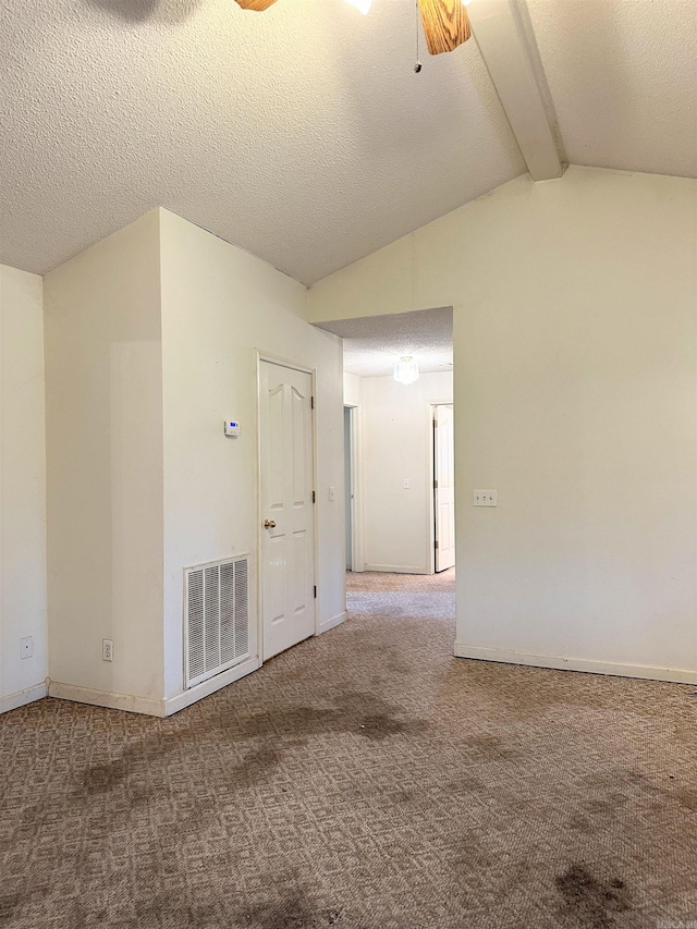 carpeted empty room with a textured ceiling and vaulted ceiling with beams