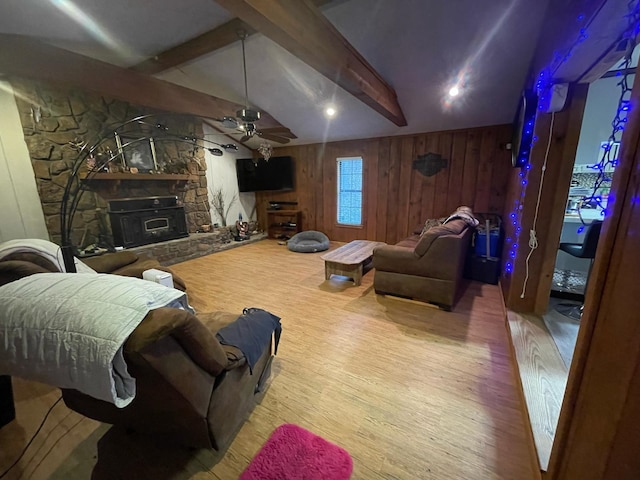 living room with light hardwood / wood-style flooring, a stone fireplace, lofted ceiling with beams, ceiling fan, and wooden walls