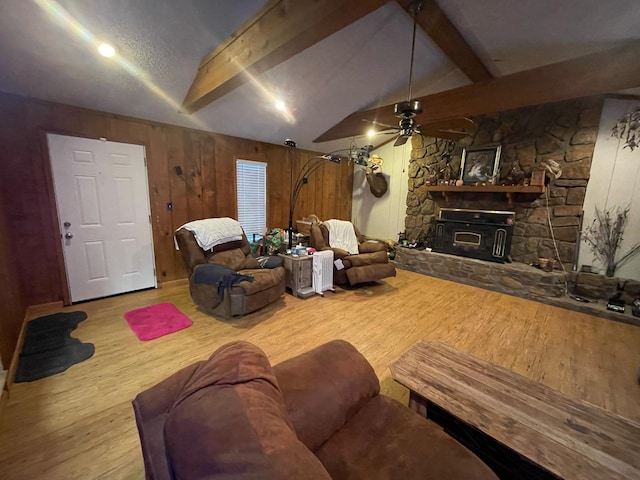 living room with wood walls, hardwood / wood-style flooring, ceiling fan, and lofted ceiling with beams