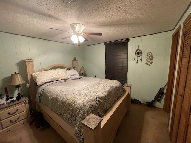 bedroom featuring ceiling fan, dark colored carpet, and a textured ceiling