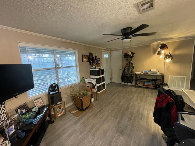 interior space featuring a textured ceiling, hardwood / wood-style flooring, and crown molding