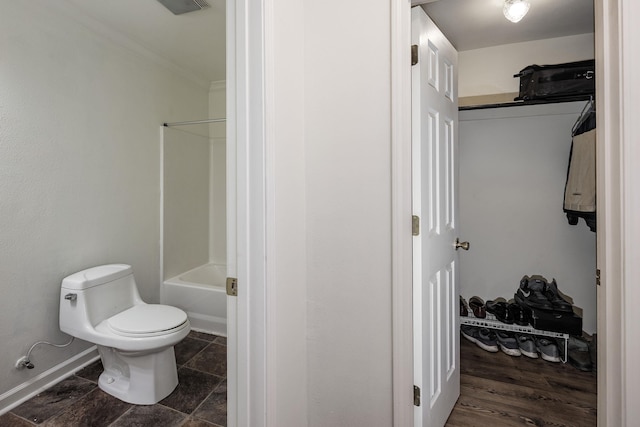 bathroom with crown molding, bathing tub / shower combination, and toilet