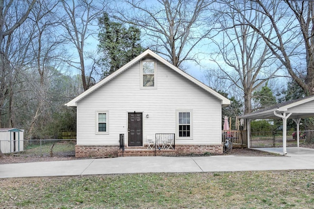 view of front of property featuring a carport and a storage shed