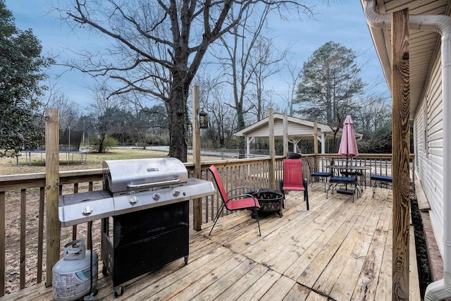 wooden terrace featuring area for grilling, a trampoline, and a gazebo