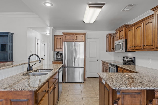 kitchen with appliances with stainless steel finishes, a center island with sink, light stone countertops, light tile patterned floors, and sink