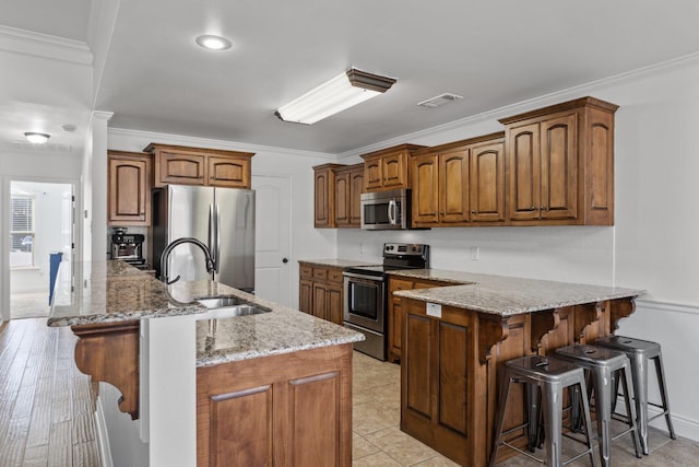 kitchen featuring appliances with stainless steel finishes, sink, a kitchen island with sink, and a breakfast bar