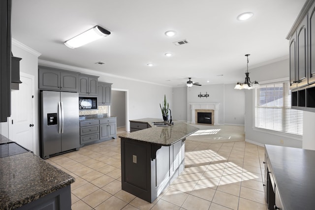 kitchen featuring stainless steel fridge with ice dispenser, a center island, sink, black microwave, and light tile patterned flooring