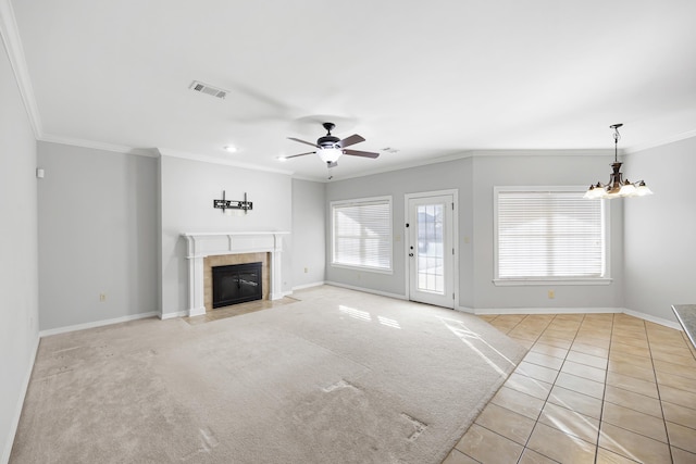 unfurnished living room featuring a fireplace, light tile patterned flooring, crown molding, and ceiling fan with notable chandelier