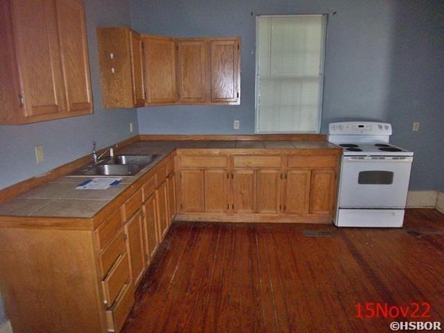 kitchen with sink, tile countertops, white electric range oven, and dark hardwood / wood-style flooring