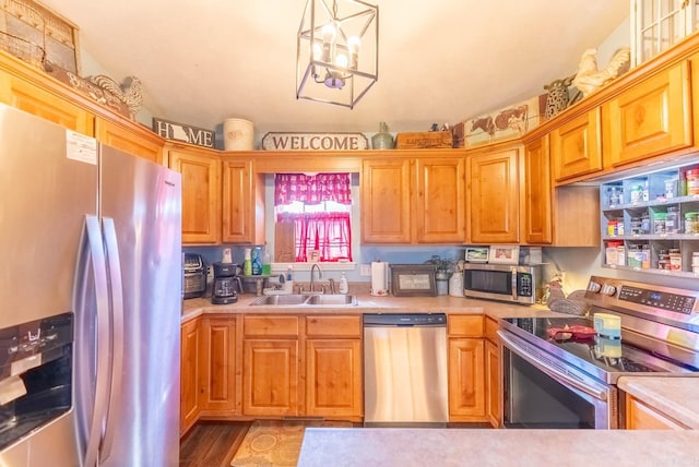 kitchen with appliances with stainless steel finishes, decorative light fixtures, sink, and an inviting chandelier