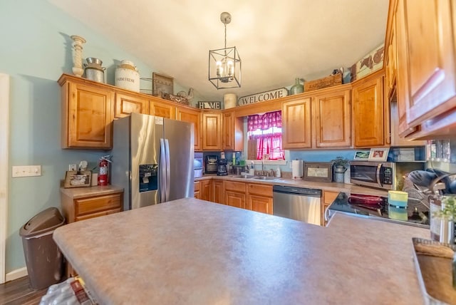 kitchen featuring appliances with stainless steel finishes, sink, a chandelier, pendant lighting, and kitchen peninsula