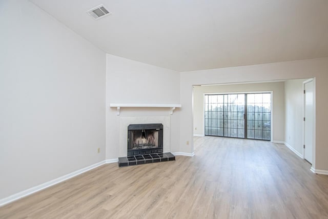 unfurnished living room with a tile fireplace and light hardwood / wood-style flooring