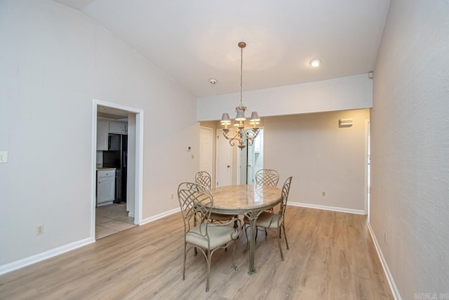 dining space featuring light hardwood / wood-style floors, lofted ceiling, and a notable chandelier